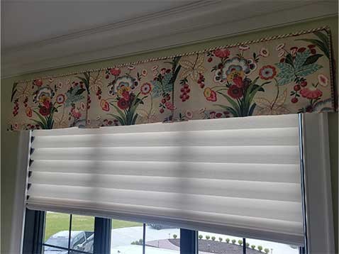 Window with hanging shades and a floral valance